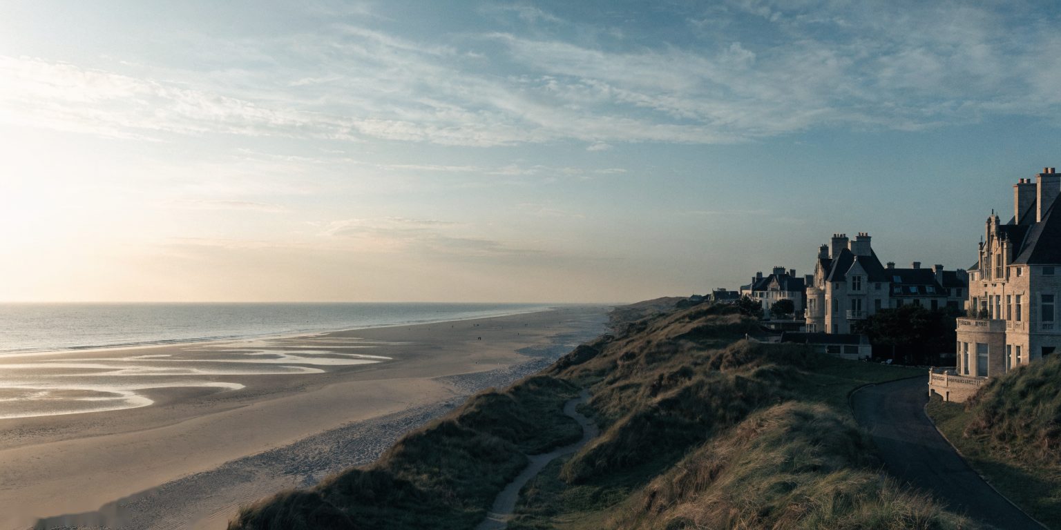 Vue aérienne de Rivelune-sur-Mer à l'heure dorée, villas Art Déco posées sur les dunes.